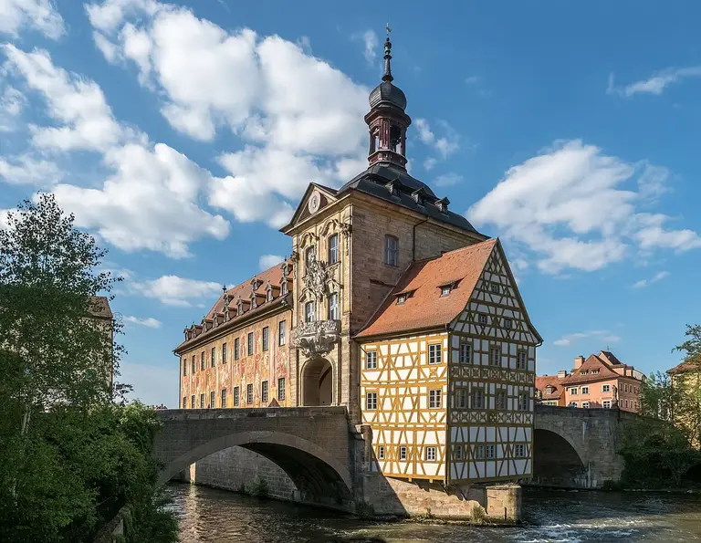 Das Alte Rathaus von Bamberg auf seiner Insel in der Regnitz mit Fachwerkanbau und bemalter Fassade.