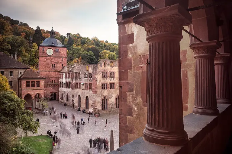 Das Heidelberger Schloss aus rotem Sandstein thront über der Stadt Heidelberg, im Hintergrund die bewaldeten Hänge des Königstuhls.