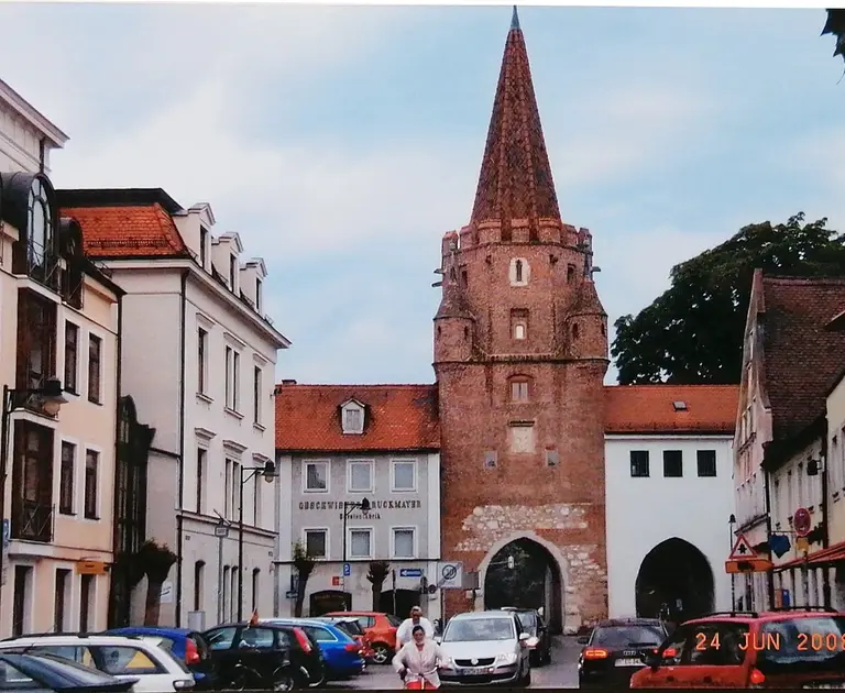 Das mittelalterliche Kreuztor in Ingolstadt, ein weißes spätgotisches Stadttor mit hohem Mittelturm und Spitzhelmen, vor blauem Himmel