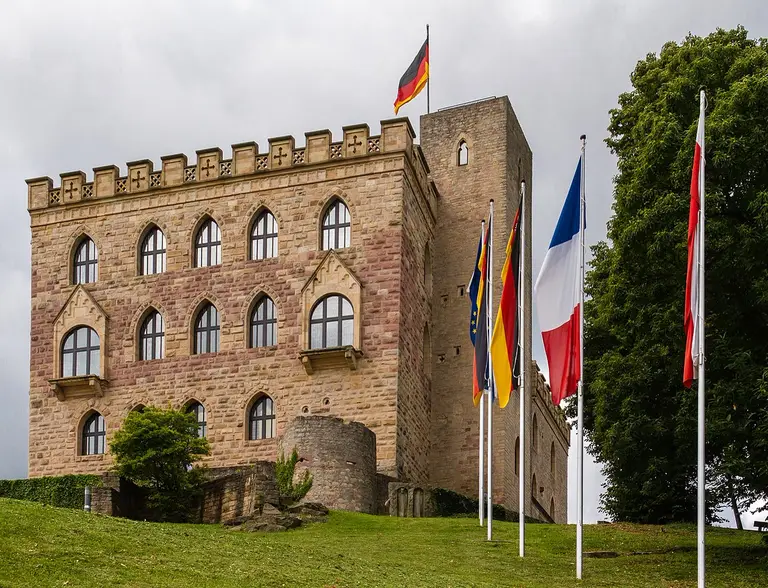 Das Hambacher Schloss bei Neustadt an der Weinstraße auf einem bewaldeten Hügel, Ostseite bei Tageslicht.