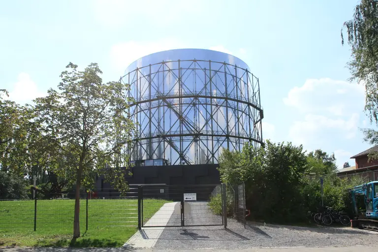 Der Gasometer Pforzheim, ein großer zylindrischer ehemaliger Gasspeicher, der heute als 360-Grad-Panorama-Ausstellungshalle dient, vor blauem Himmel