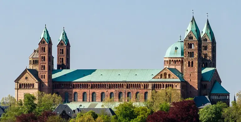 Südseite des Speyerer Doms, einer romanischen Kathedrale aus rotem Sandstein mit Türmen und Kuppel unter blauem Himmel