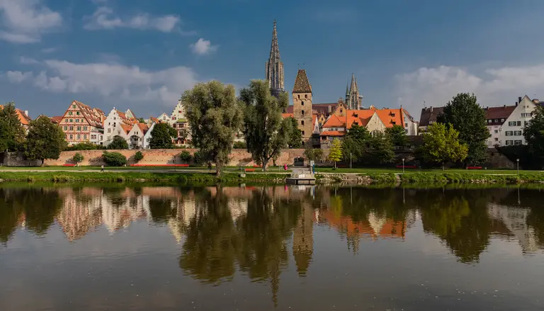 Blick über die Donau auf die Ulmer Altstadt mit dem Ulmer Münster und seinem hohen Kirchturm, gespiegelt im Wasser
